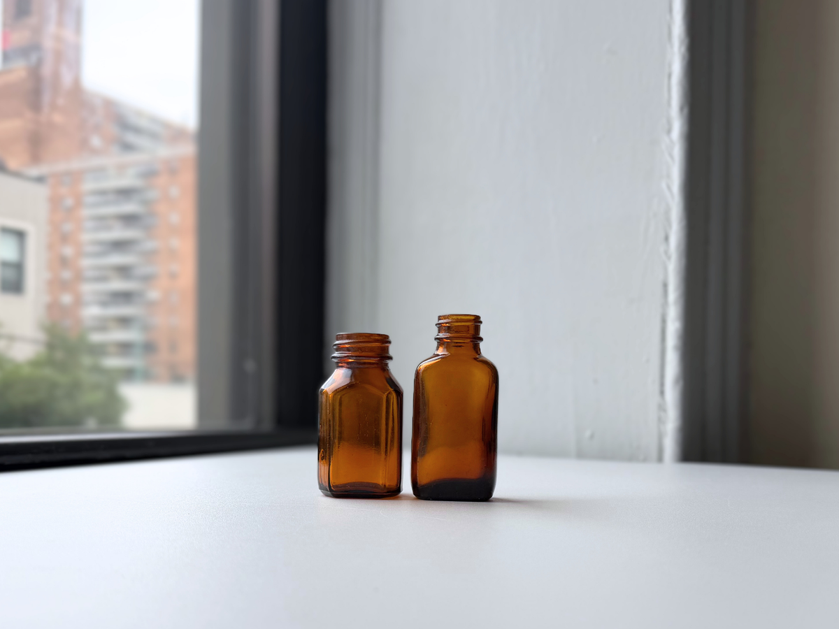 Set of two 1940s amber glass pharmacy bottles displayed on a windowsill.