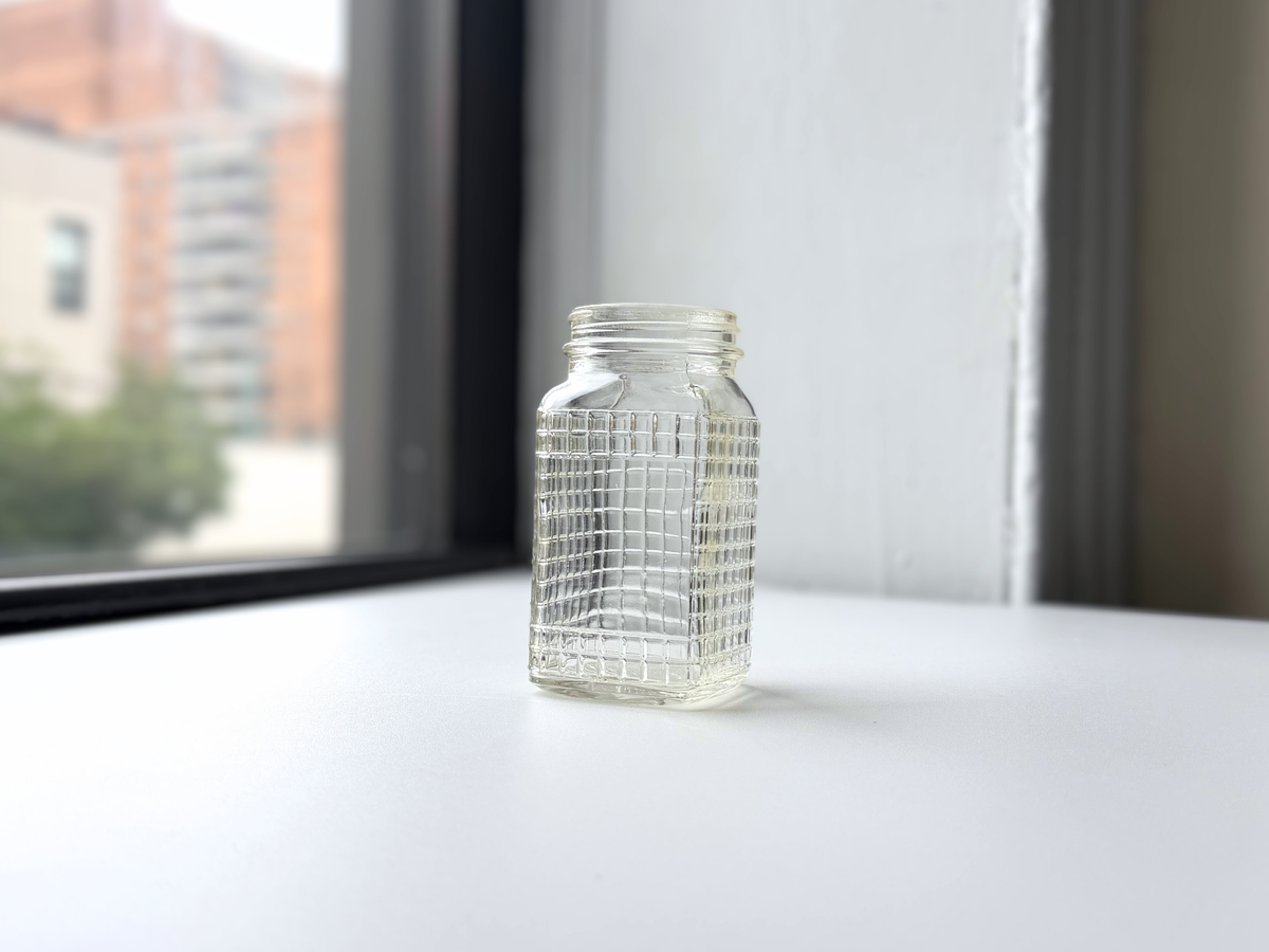 Ball waffle glass jar with crosshatch texture displayed on a windowsill, 1930s.