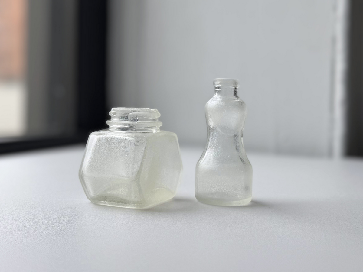 Set of two sea-worn ink bottles, Waterman's and Hazel Atlas, displayed on a windowsill.