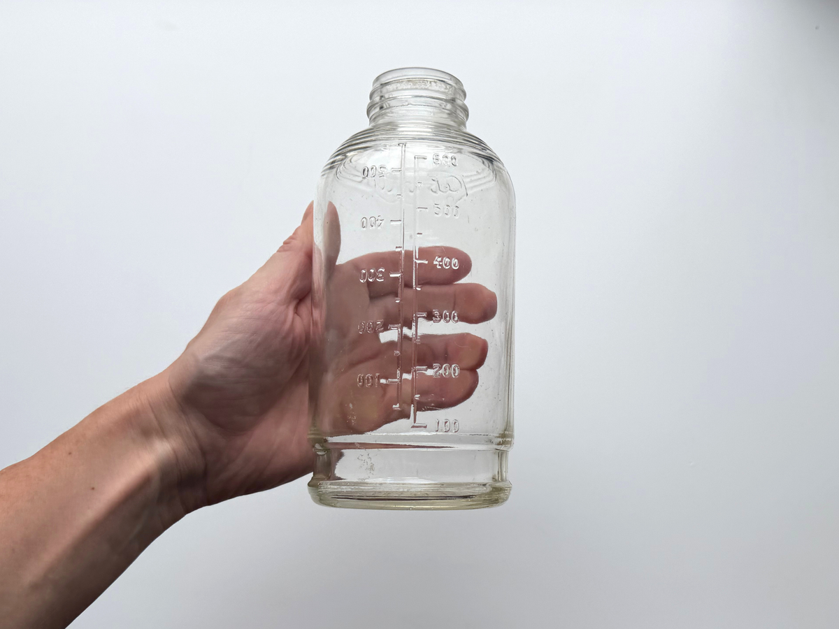 Hand holding a clear glass Abbott Laboratories medicine bottle to show scale.