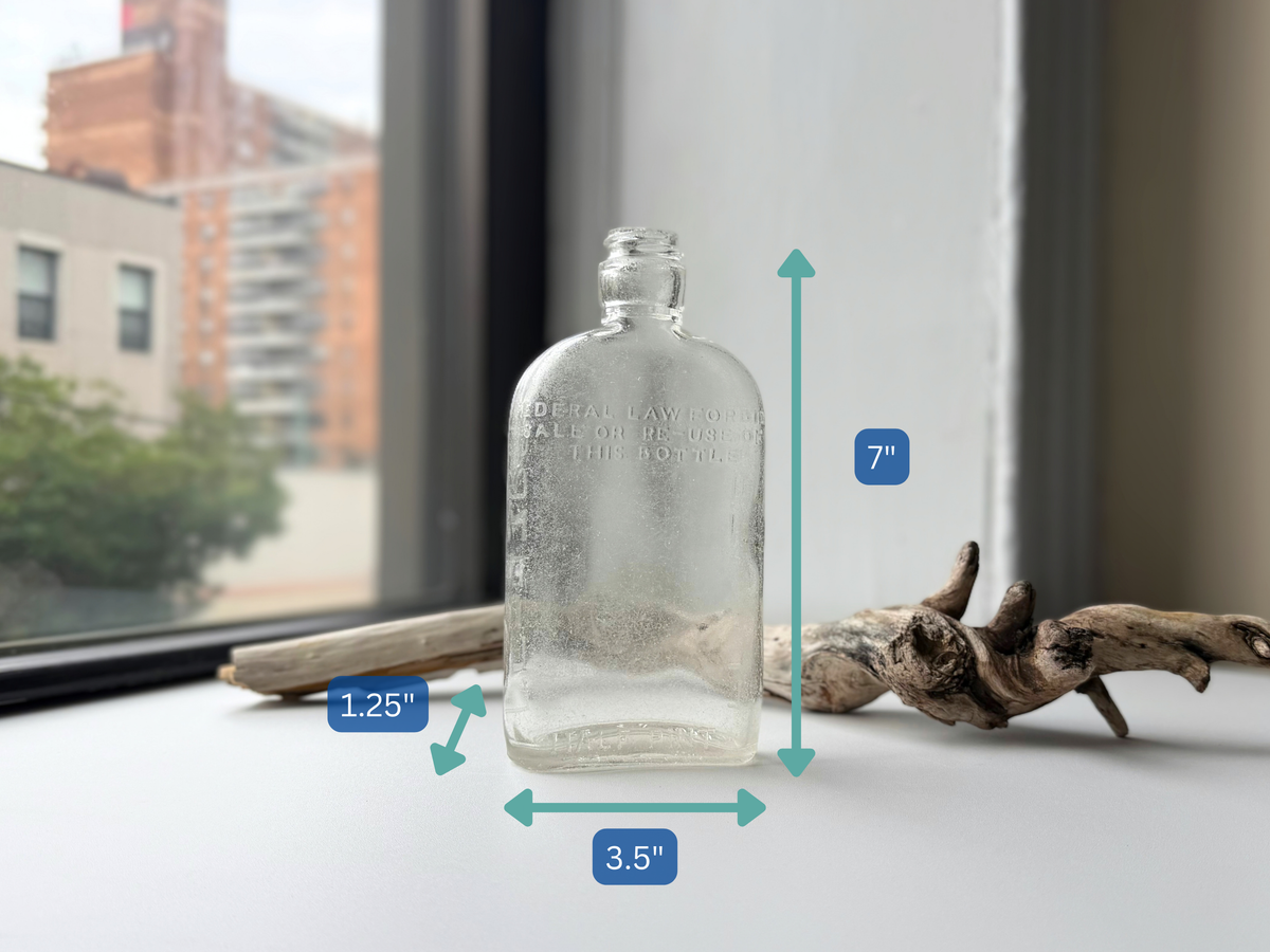 Clear sea-worn G. O'Neill flask on a windowsill with dimension arrows showing 7 inches tall, 3.5 inches wide and 1.25 inches deep.