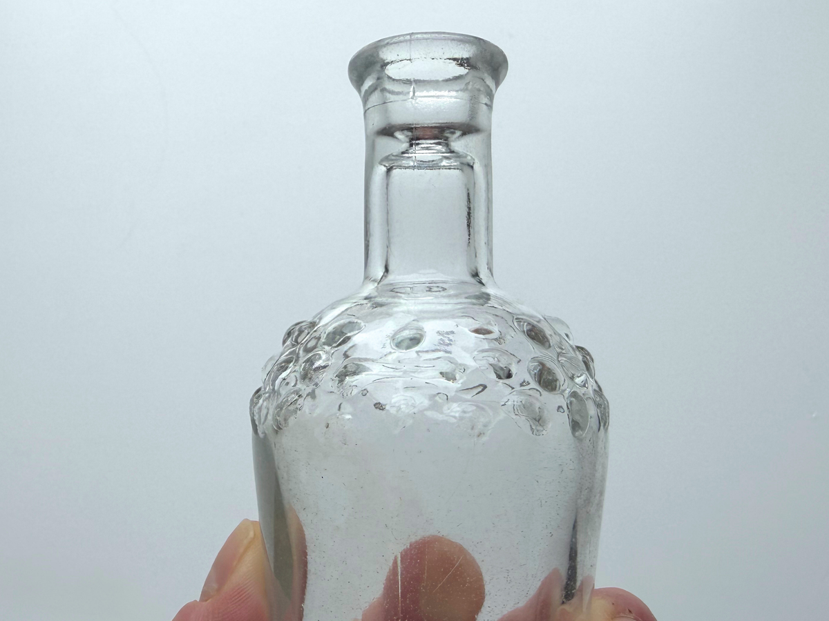 Close-up of the raised hobnail dot texture on a clear glass bud vase.
