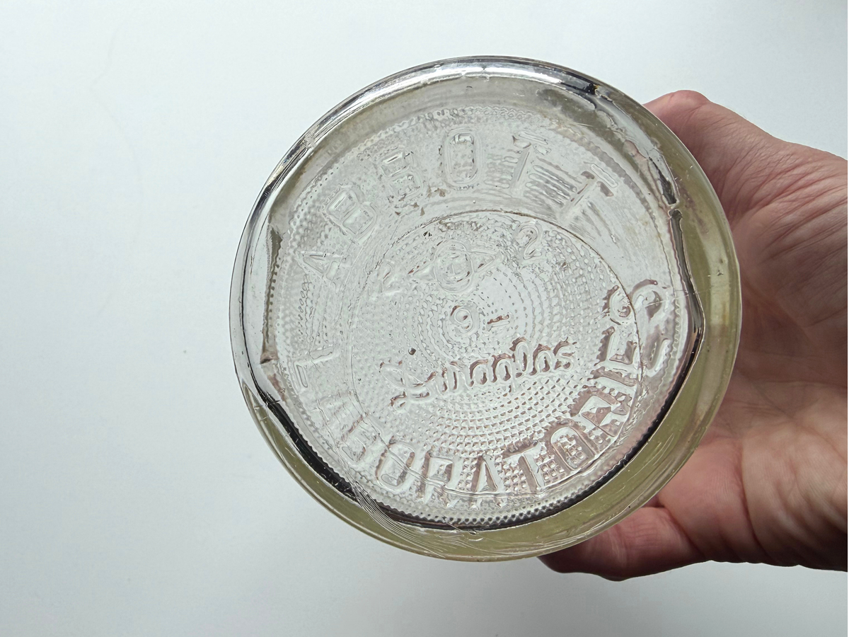 Abbott Laboratories bottle base held in hand showing embossed Abbott Laboratories Duraglas text.