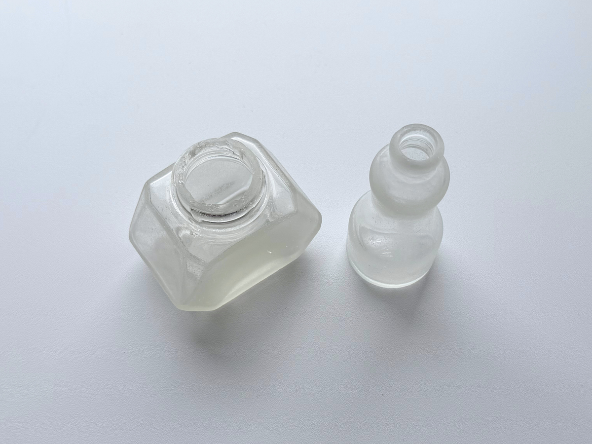 Two sea-worn ink bottles with genuine ocean patina, photographed on a gradient background.