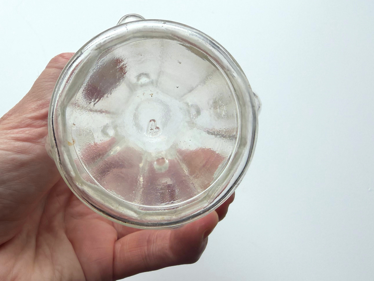 Teardrop glass bottle base held in hand showing the raised bump texture pattern.