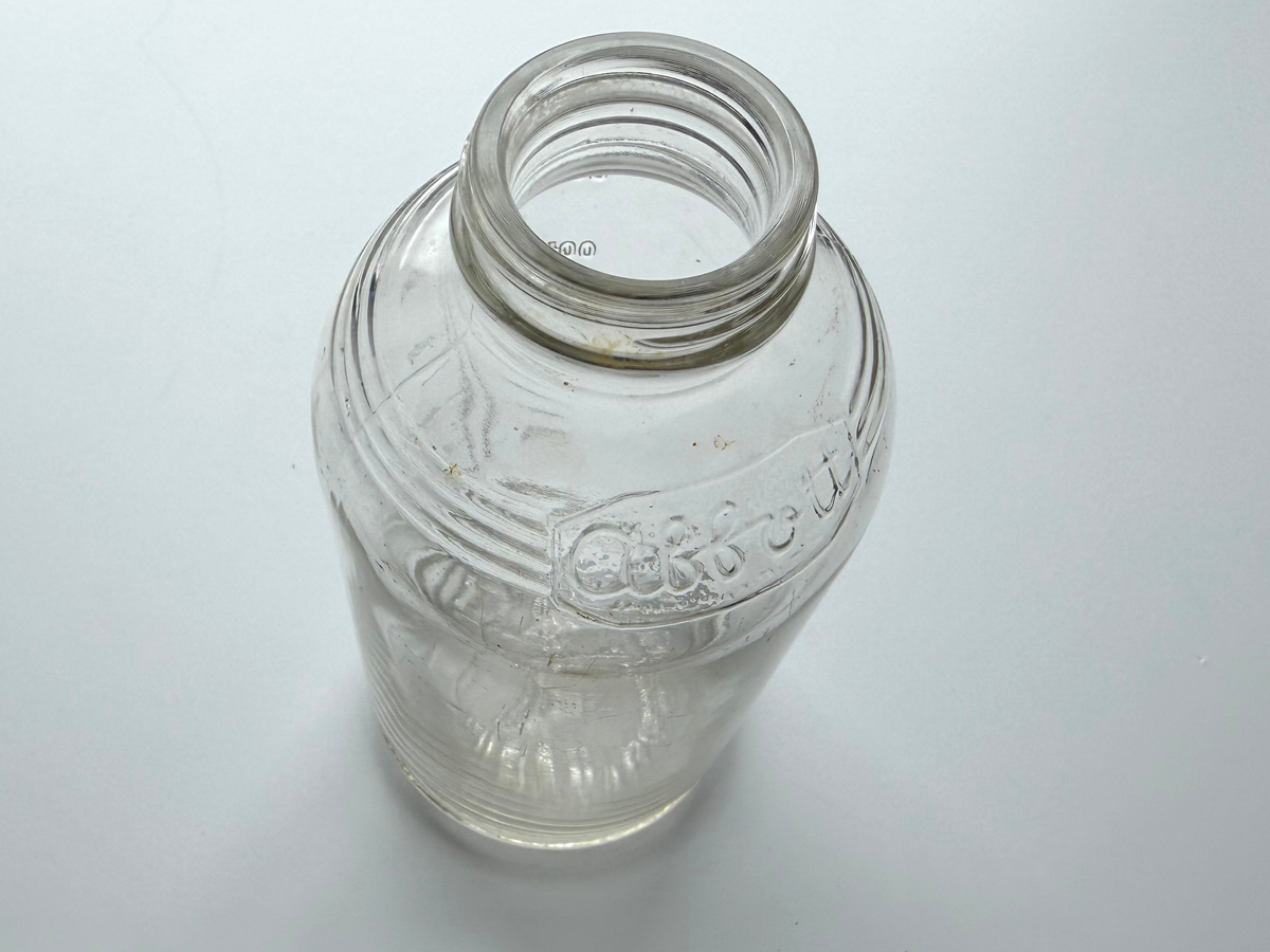 Top-down view into the open mouth of an Abbott Laboratories glass bottle.
