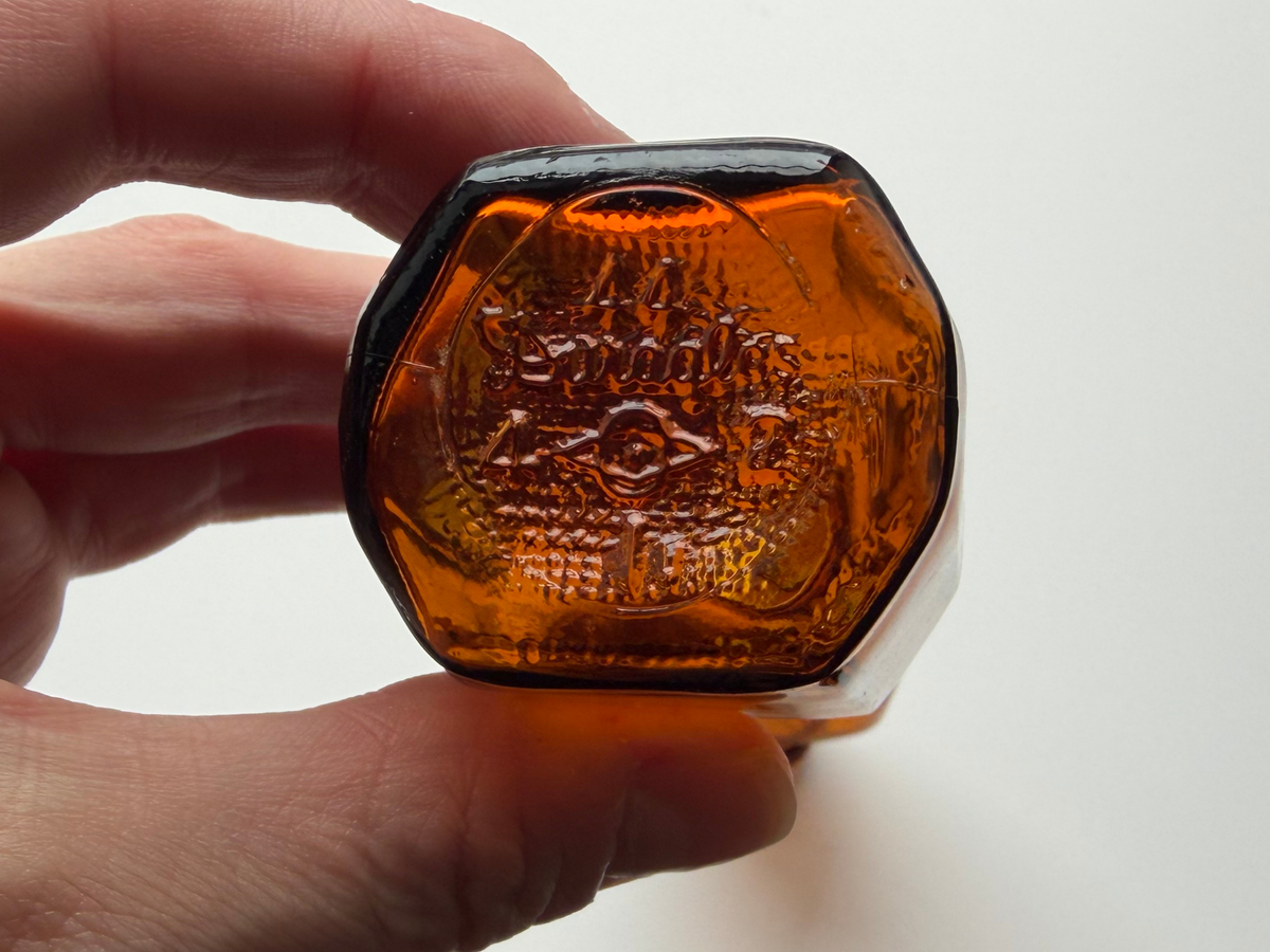 Amber glass bottle base held in hand showing the embossed Duraglas 44 marking.