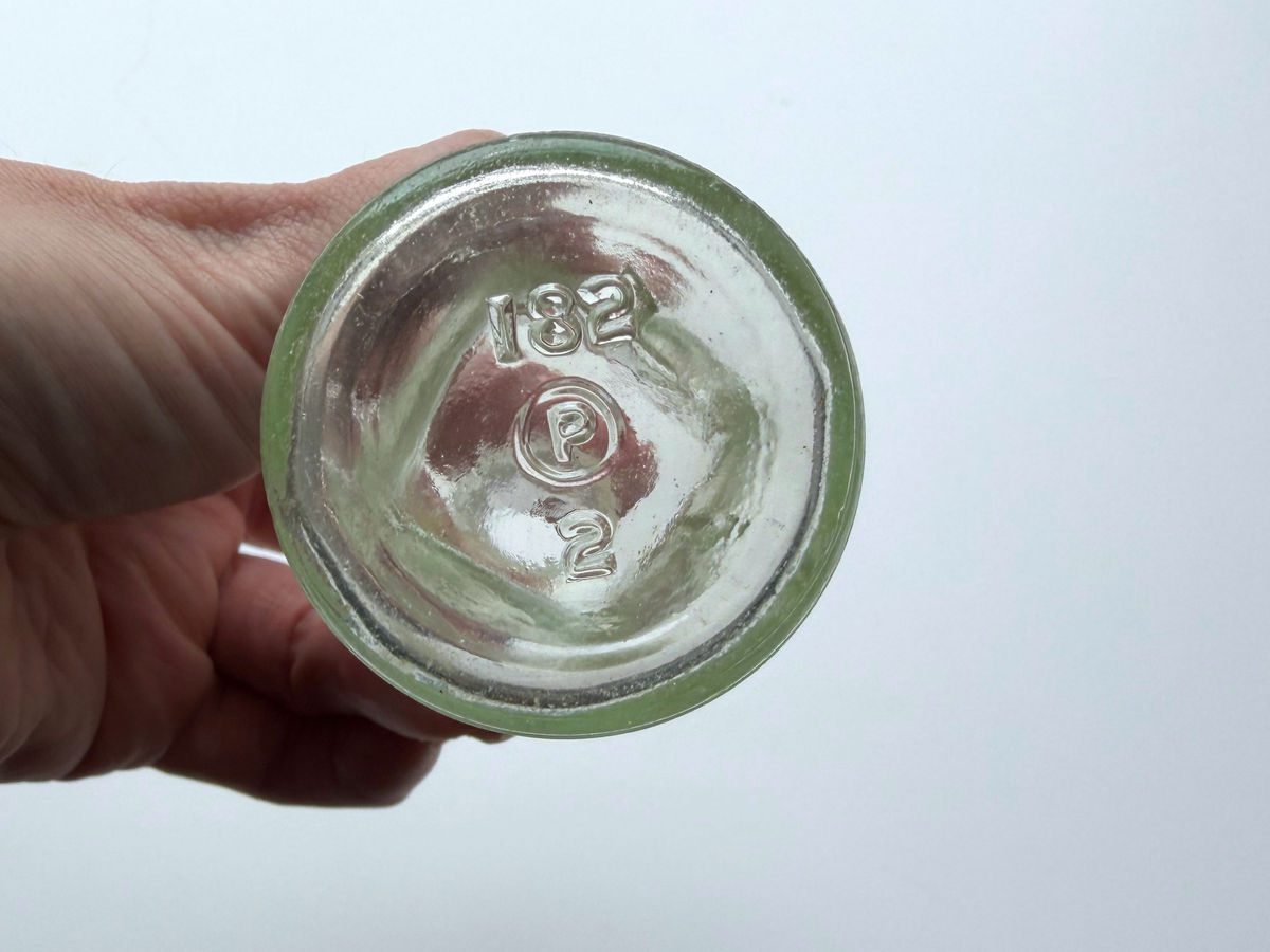 Bon Oil bottle base held in hand showing the embossed olive branch pattern.