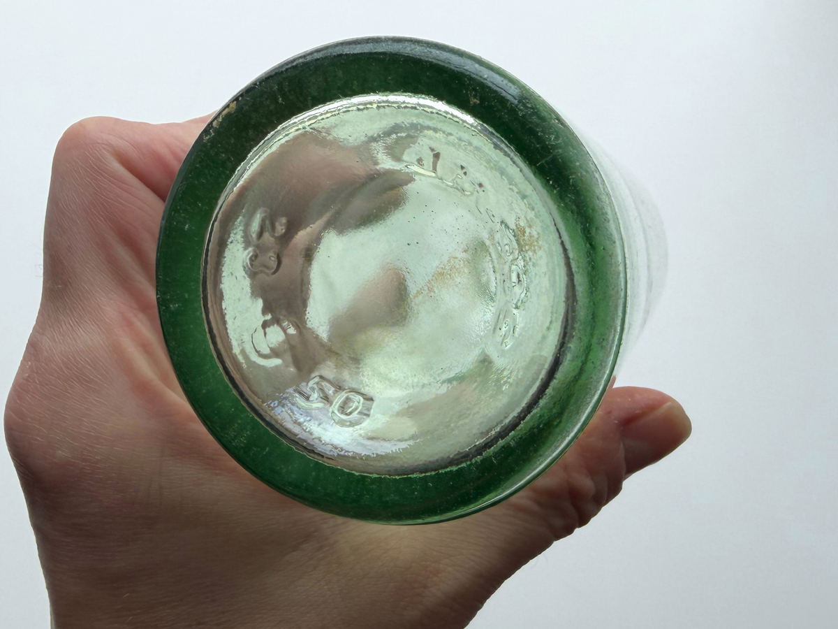 Pale green glass bottle base held in hand showing embossed 4/5 pint capacity mark.