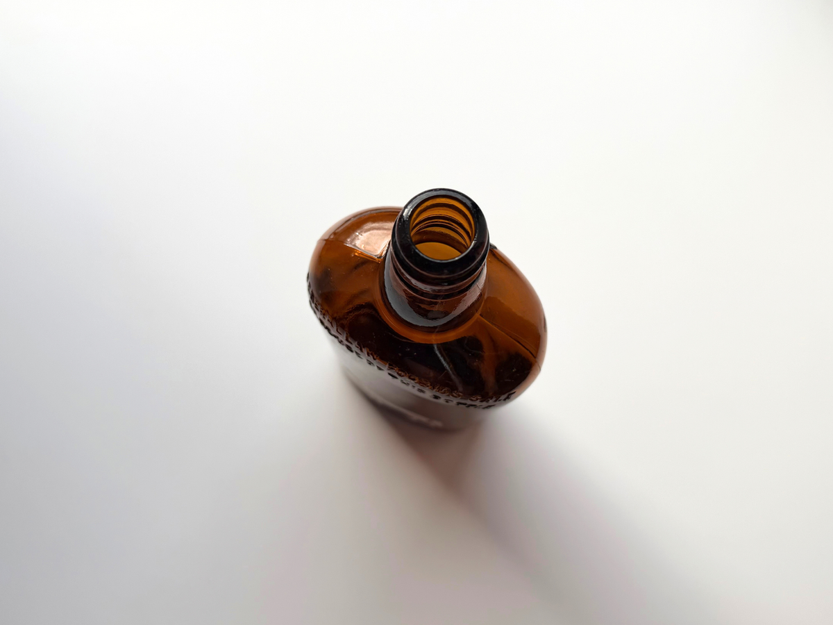 Top-down view of the open threaded mouth of a vintage amber White Horse bottle, with embossed lettering visible along the shoulder.