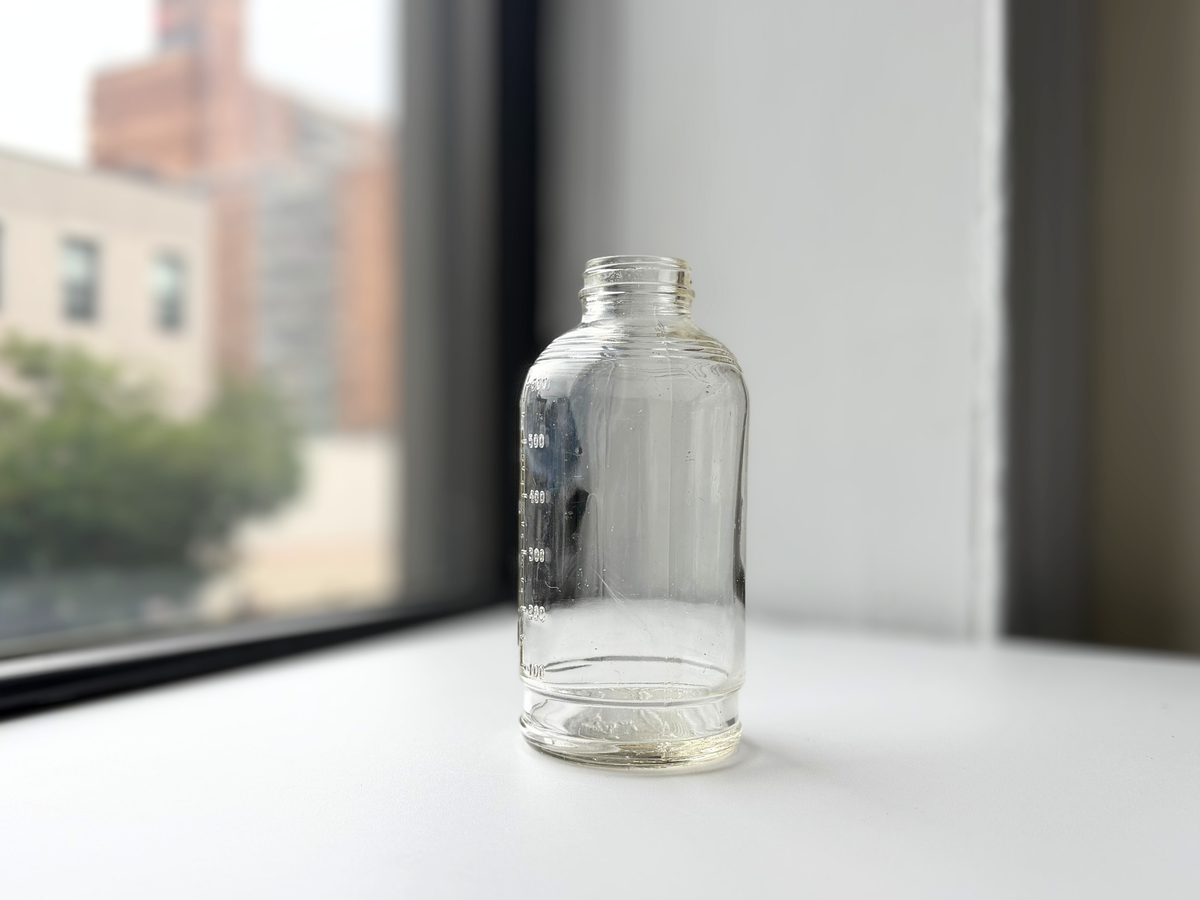 Clear glass Abbott Laboratories bottle on a windowsill at an angle.