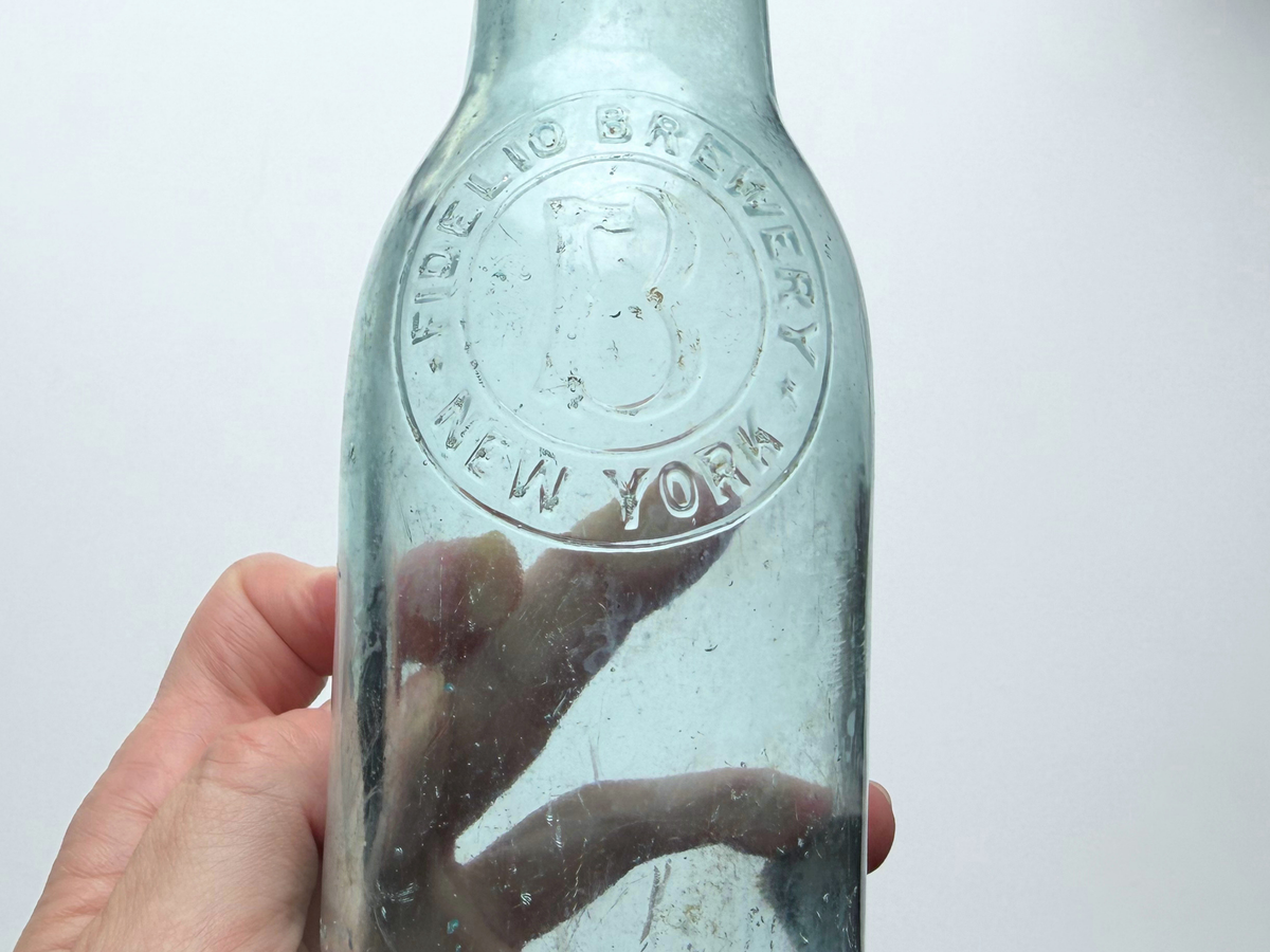 Close-up of embossed Fidelio Brewery New York text within a raised circular slug plate.