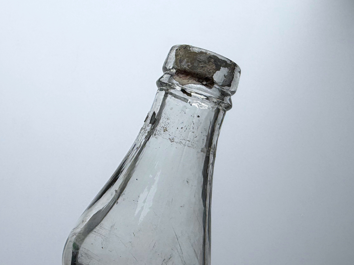 Close-up of the neck of a James Martin whiskey bottle showing remnants of the original cap label.