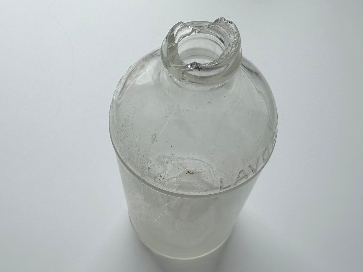 Top-down view into the sea-worn mouth of a frosted Lavoris bottle with LAVORIS lettering visible on the shoulder.