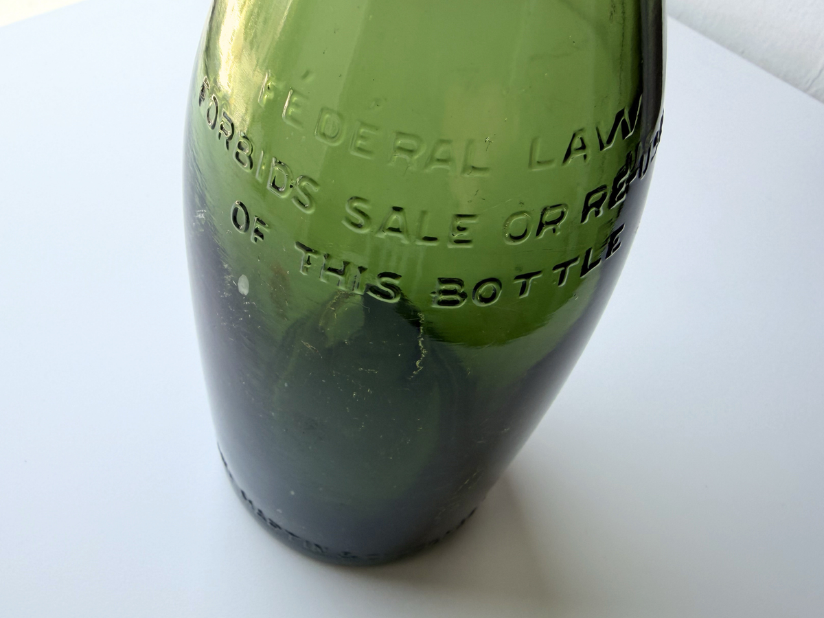 Close-up of embossed lettering on a Remy Martin green glass bottle.