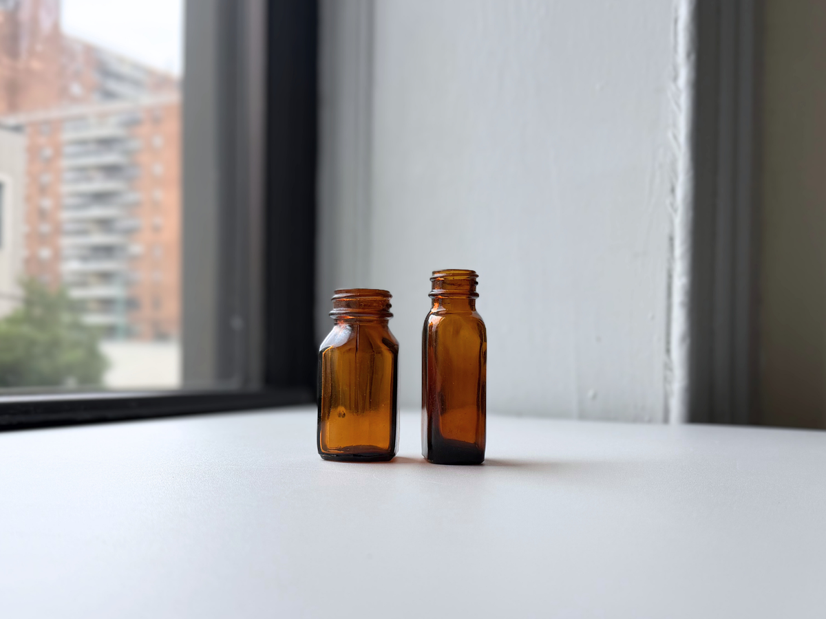 Amber glass bottle pair on a windowsill at an angle.