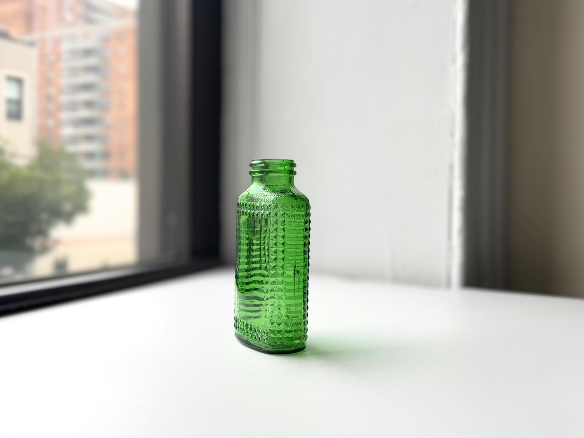 Close-up of the hobnail texture on a vintage kelly green Airwick glass bottle
