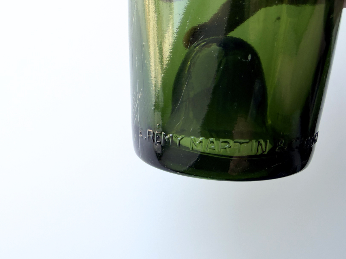 Remy Martin bottle held in hand showing the embossed oval line design.