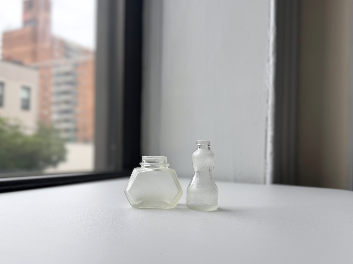 Set of two sea-worn ink bottles on a windowsill with Brooklyn brownstones in the background.