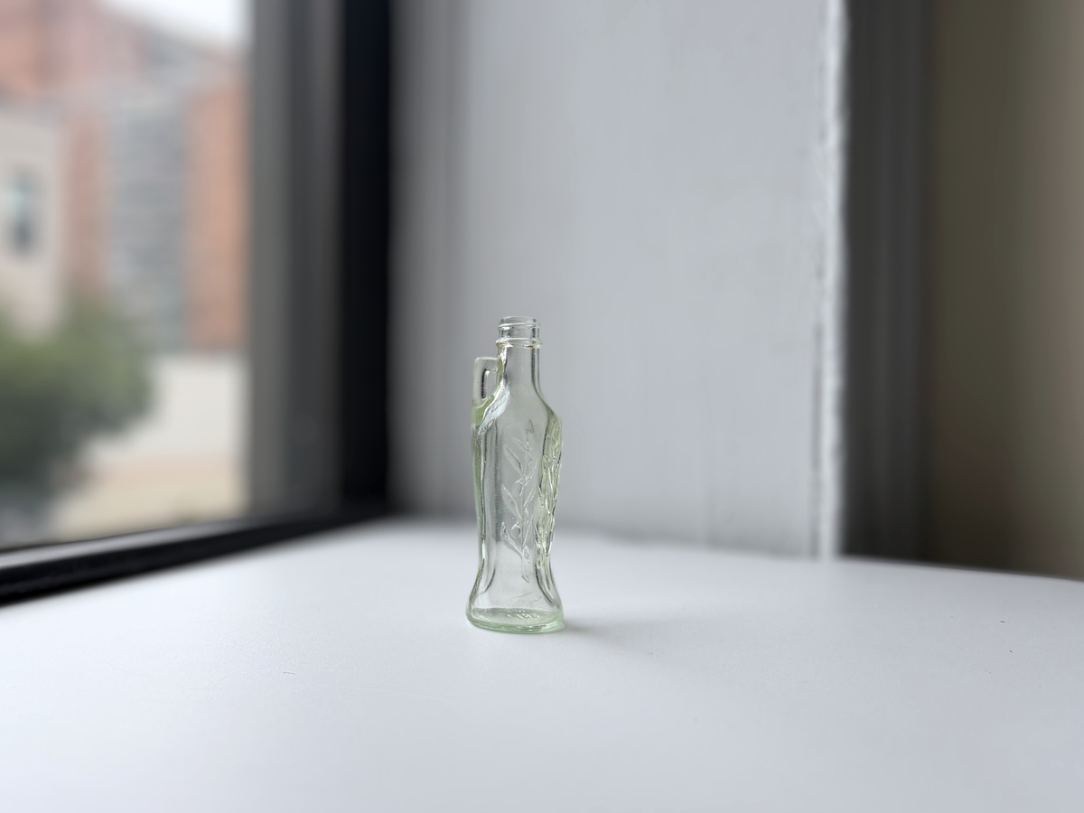 Vintage Bon Oil bottle on a windowsill, side profile showing the neck handle.