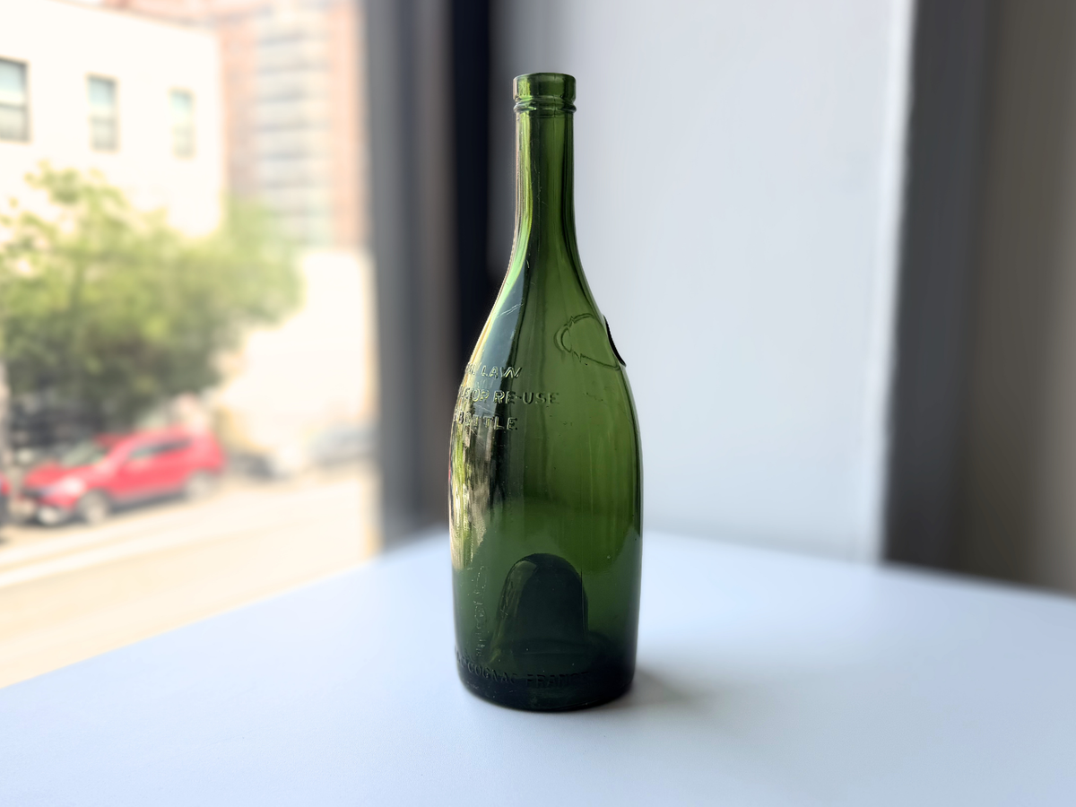 E. Remy Martin & Co green glass bottle on a windowsill at an angle.