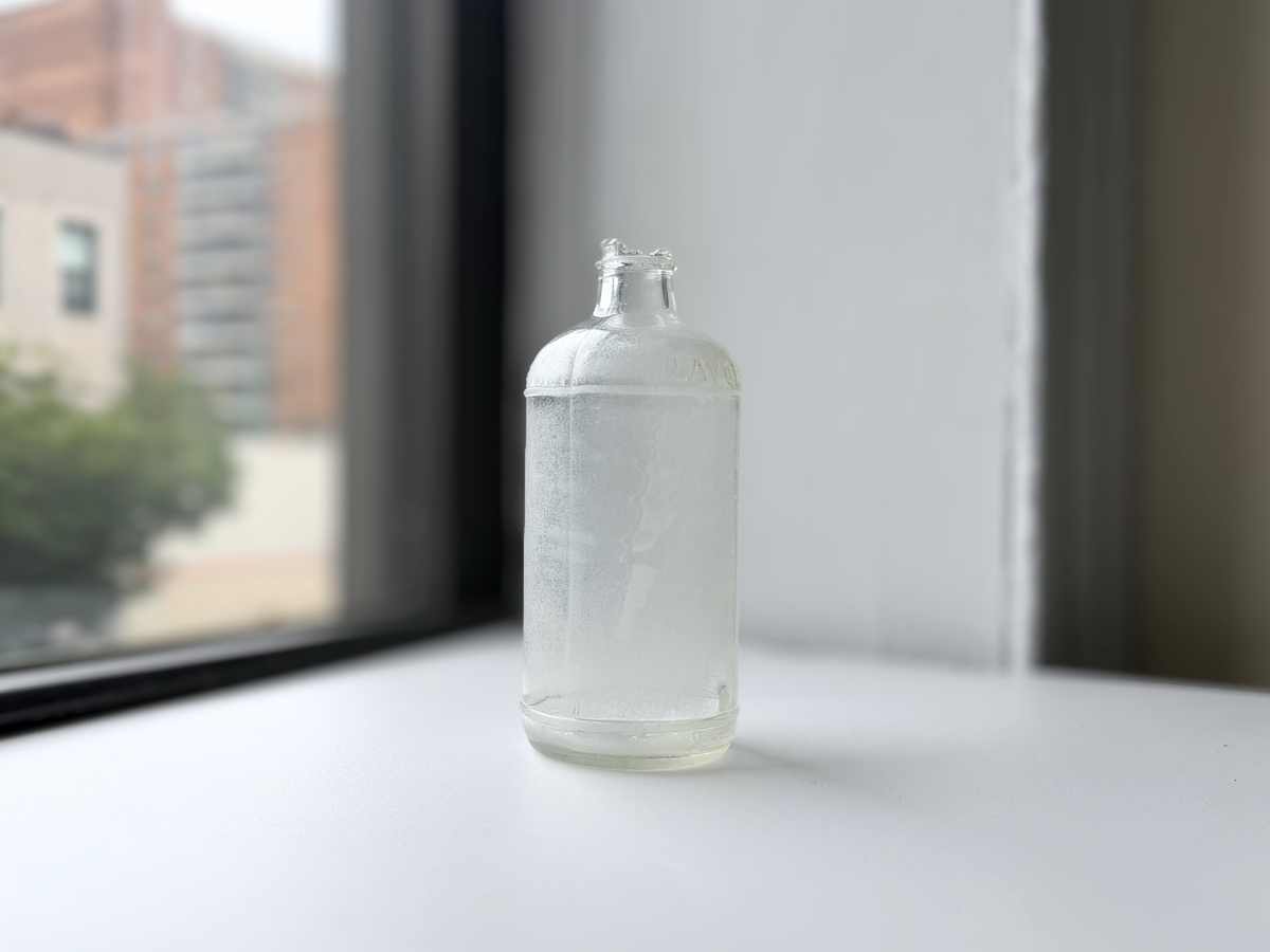 Vintage 1952 Lavoris bottle with heavy sea glass frosting, photographed on a windowsill.