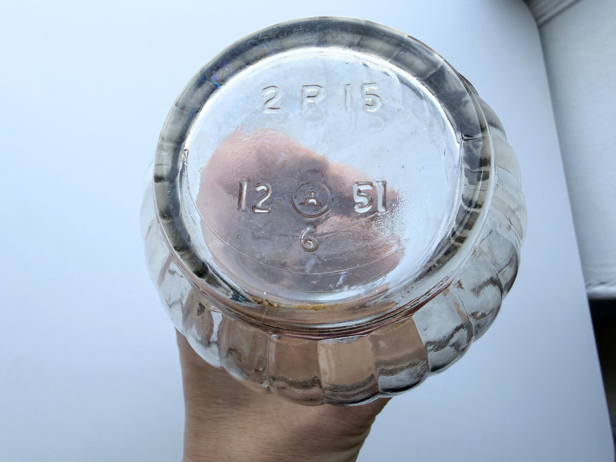 Base of a vintage genie bottle held up to show the glassmaker mark and the 1951 date code