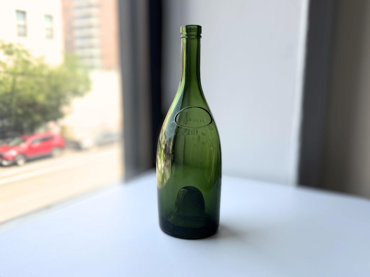 Remy Martin green glass bottle displayed on a windowsill with Brooklyn brownstones in the background.