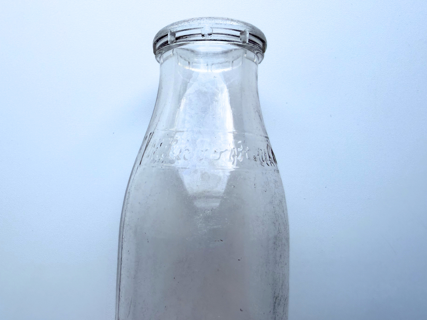 Close-up of embossed lettering on a vintage Milk for Health glass milk bottle from 1953