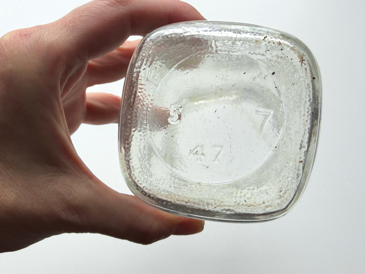 Anchor Hocking mason jar base held in hand showing the embossed maker's mark.