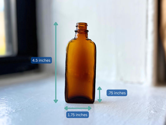 Dimensional reference photo of 1942 amber medicine bottle showing measurements - 4.5 inches tall, 1.75 inches wide, 0.75 inches deep - vintage apothecary bottle with ribbed sides and square base - antique pharmaceutical glass sizing for collectors an