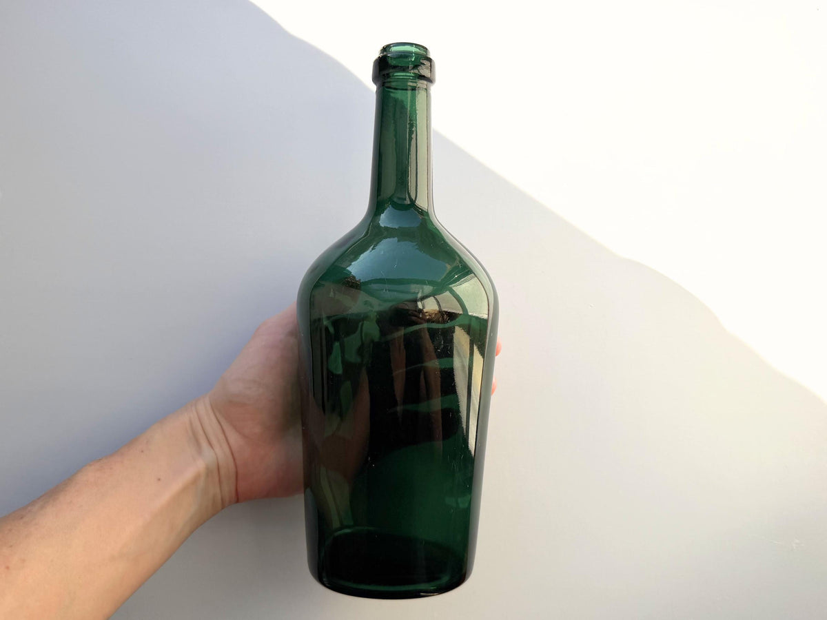 Forest green bottle side view showing broad shoulder profile and deep saturated mid-century glass color