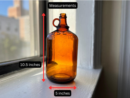 Vintage amber glass bottle with a carrying handle. The bottle has raised lettering that says ROSE-X and ONE GALLON. The bottle is 10.5 inches tall and 5 inches wide.