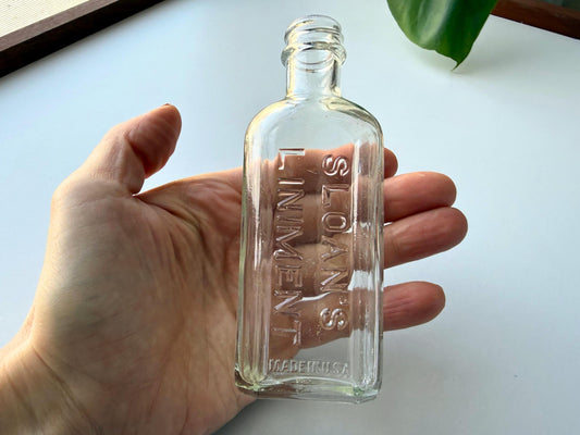 Authentic vintage Sloan's Liniment medicine bottle from 1940s-early 1950s in clear glass with embossed lettering and Made in USA base marking, perfect for apothecary collectors and vintage pharmacy displays.