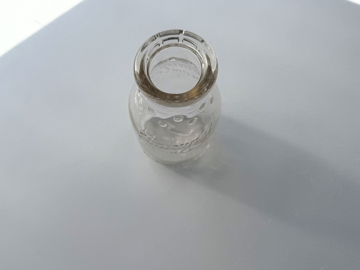 Elmhurst Cream Co. bottle top angle view showing mouth opening and clear glass dairy bottle form from above