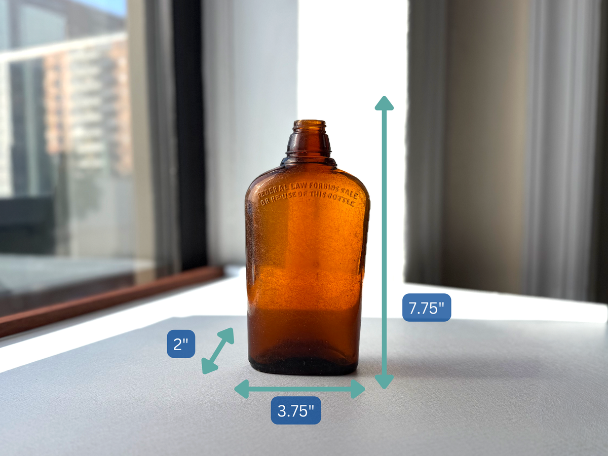 Federal Law wide-shoulder amber flask held in hand for scale, 7.75 inch seaworn amber spirits form NYC recovery