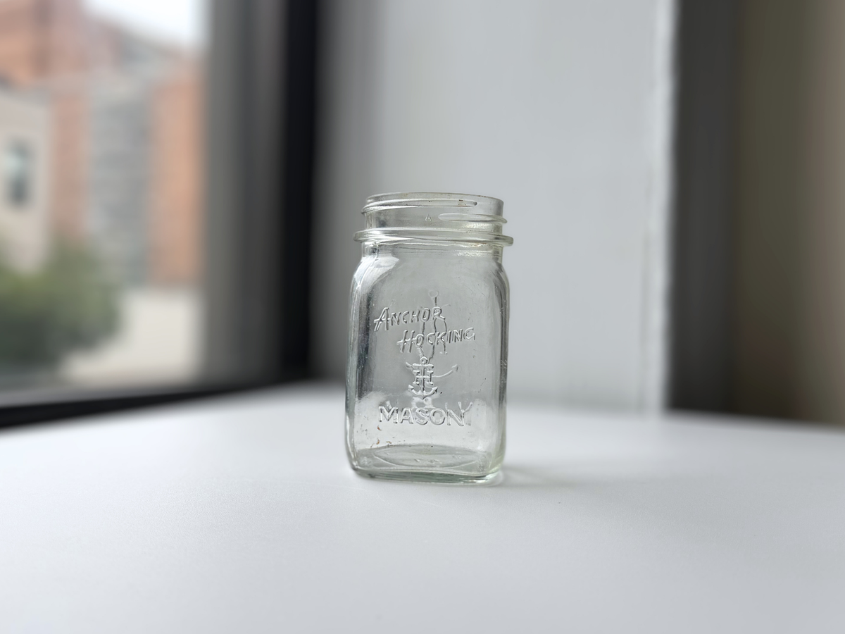 Clear glass Anchor Hocking mason jar shown at an angle on a windowsill.