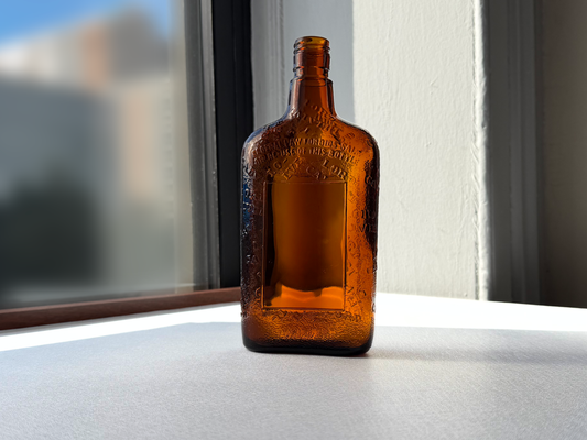 Lord Calvert 1952 amber whiskey flask angled left view, vintage American spirits bottle recovered from NYC