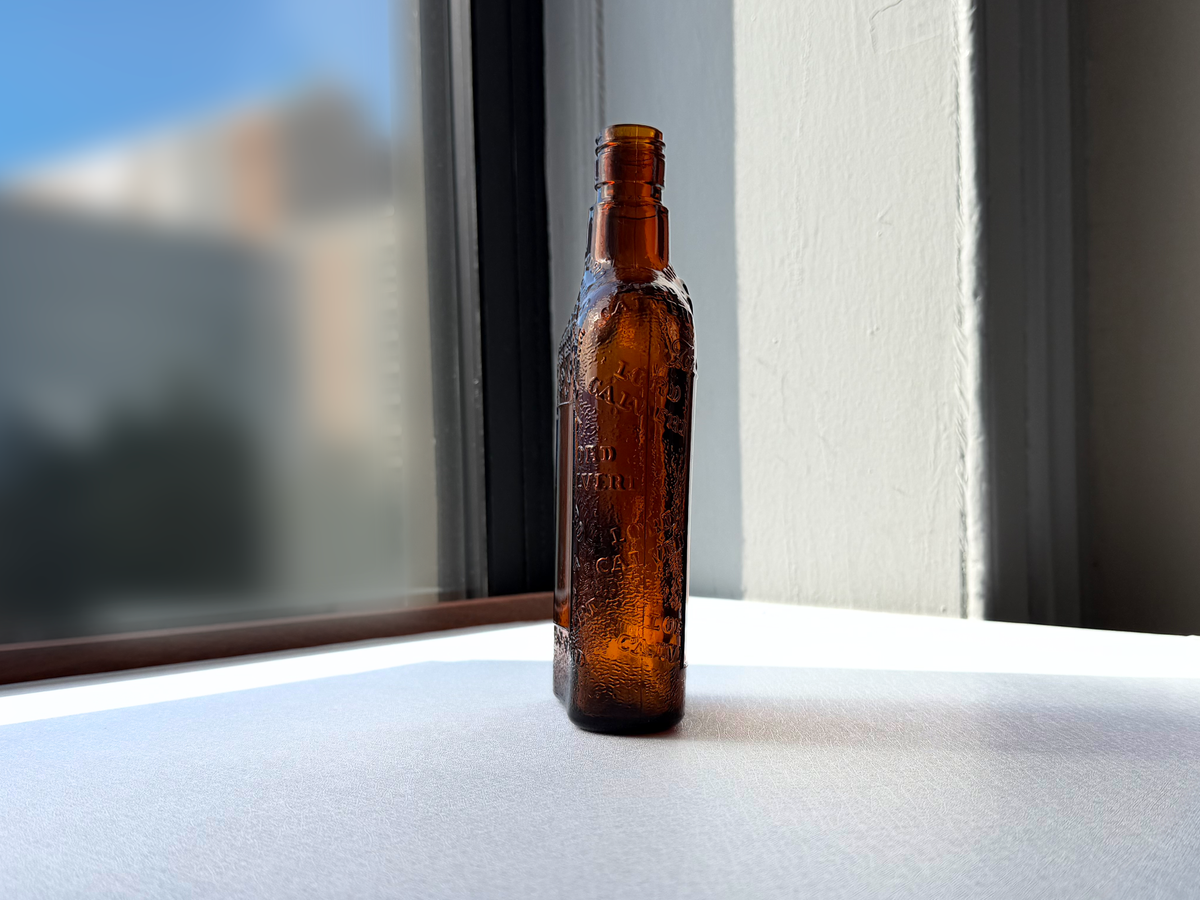 Lord Calvert 1952 amber whiskey flask held in hand showing scale, Men of Distinction vintage glass NYC