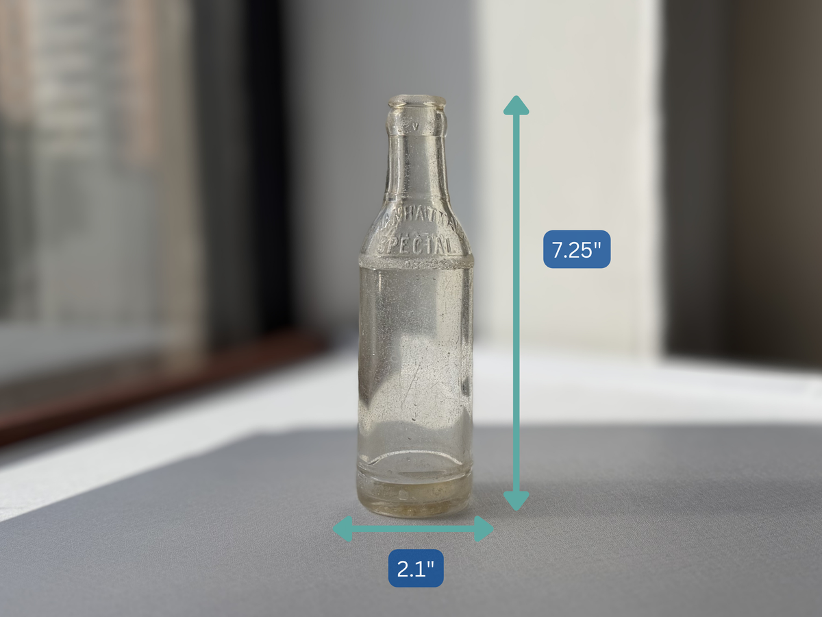Manhattan Special espresso soda bottle angled right view, tall clear glass vintage NYC beverage bottle