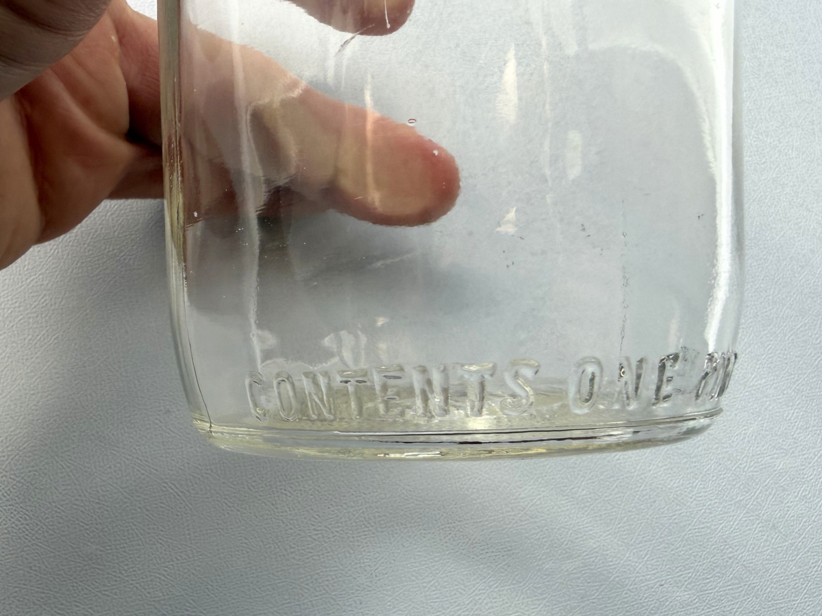 No Deposit 1954 milk bottle side view held in hand, clear embossed glass vintage dairy bottle NYC