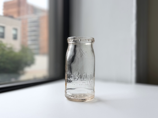 Hegeman Farms clear glass milk bottle displayed on a windowsill, 1950s Queens NY dairy.