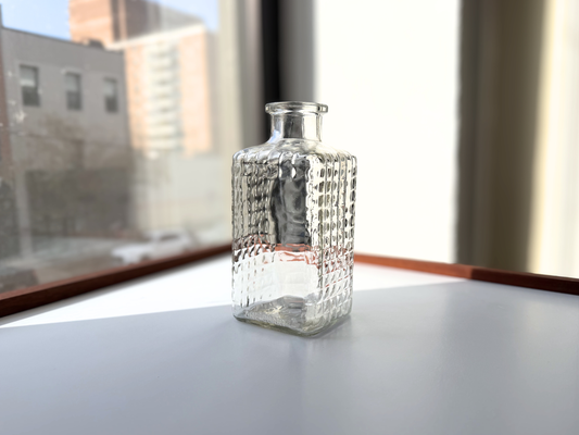 Vintage clear glass studded decanter, front view in natural window light