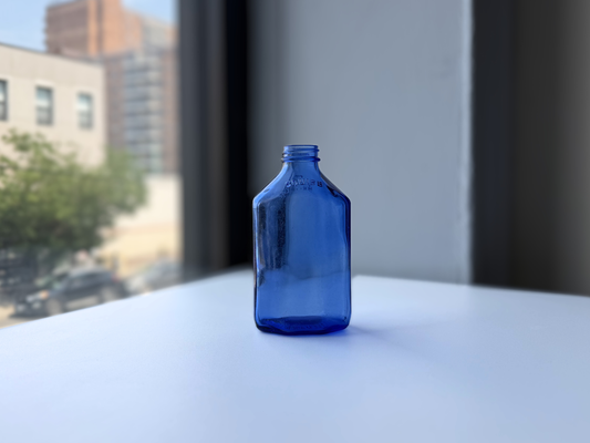 Large periwinkle blue Squibb glass medicine bottle, side view in natural light