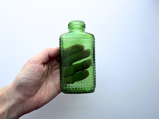 Vintage kelly green Airwick hobnail glass bottle shown from the side