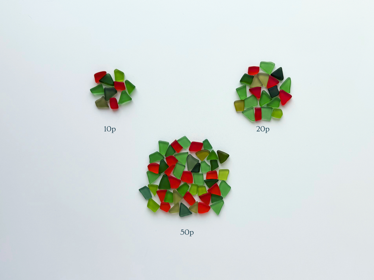 Three separate piles of holly-red and green tumbled sea glass showing the relative size difference between the 10, 20, and 50 piece set options available in this listing.