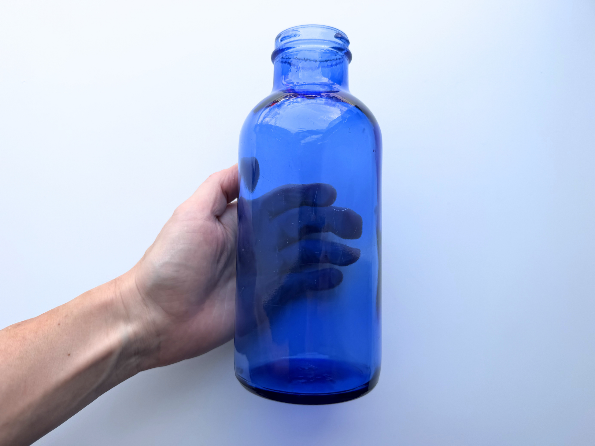 Hand holding a vintage cobalt blue glass pharmaceutical bottle