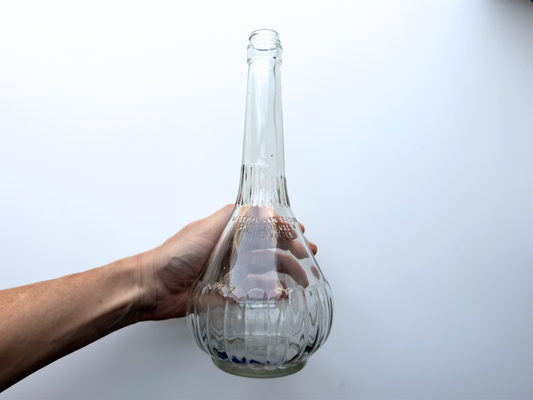 Hand holding large genie-shaped clear glass bottle for scale