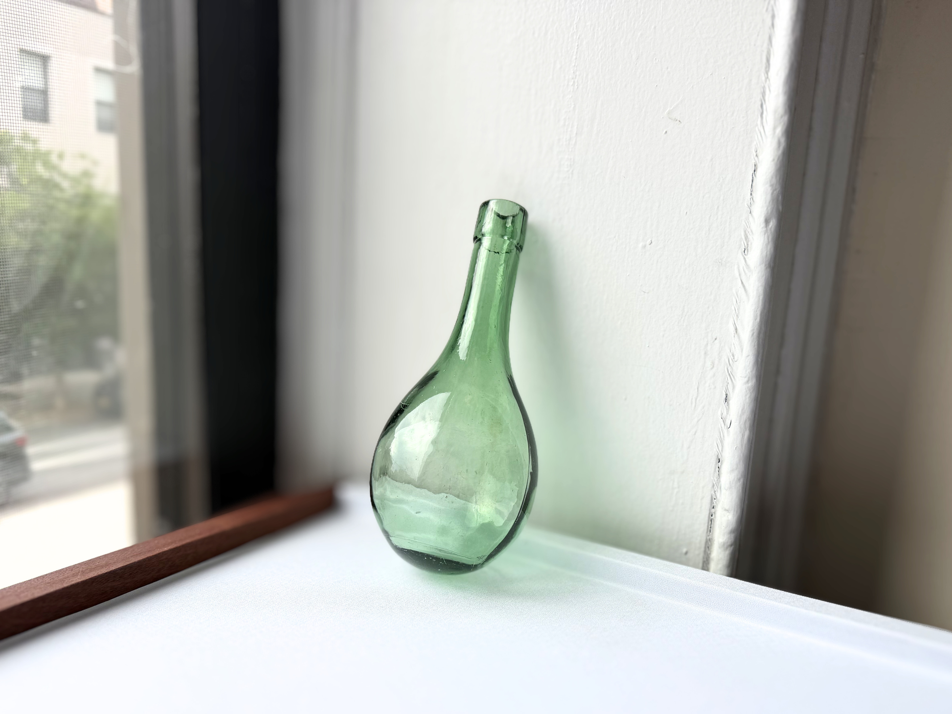 Vintage green teardrop glass bottle displayed upright, styled as bar cart or shelf decor