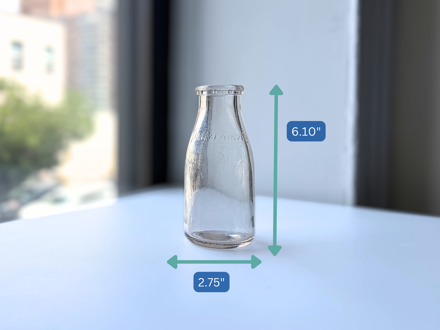 Vintage clear glass Milk for Health milk bottle shown in side profile